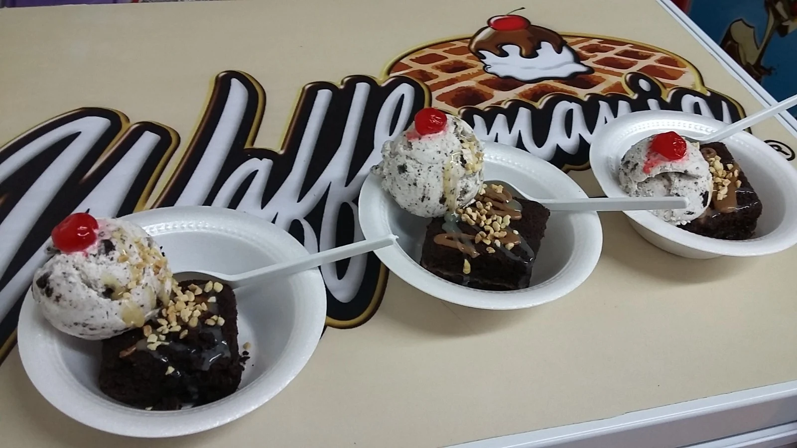 Postres con helado junto al letrero de Wafflemania